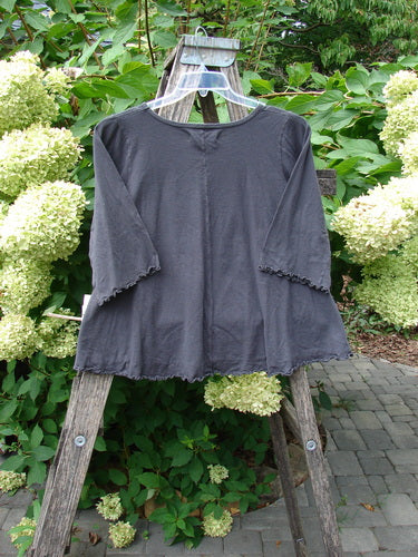 Barclay NWT Three Quarter Sleeved Crop Cafe Tee Many Fish Black Sand Size 0, displayed on a hanger over a step-ladder, showcasing its scoop neckline, flared sleeves, and organic cotton texture.