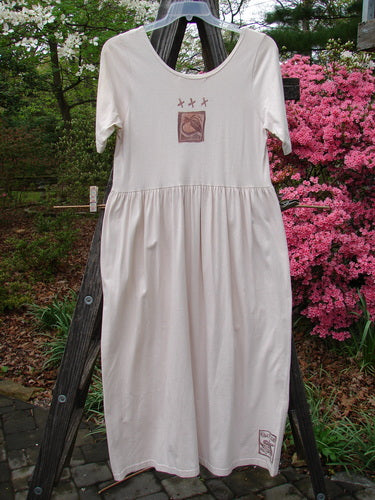 1996 Short Sleeved Simple Dress Pear Birch Bark Size 0 hanging on a clothesline, showcasing its organic cotton fabric, slightly deeper rounded neckline, drop empire waist seam, and full sweeping skirt.