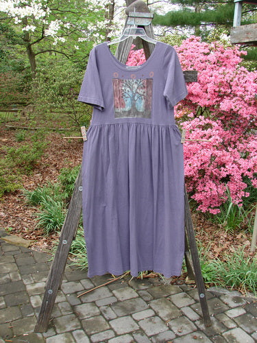 1996 Short Sleeved Simple Dress Tree of Life Purple Martin Size 0 displayed on a wooden rack, showcasing a rounded neckline, drop empire waist, and full sweeping skirt with signature Blue Fish Stamp and Tree of Life paint.