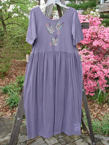 1996 Short Sleeved Simple Dress Tree of Life Purple Martin Size 0 displayed on a clothesline, showcasing a rounded neckline, drop empire waist seam, and a full sweeping skirt with painted details.