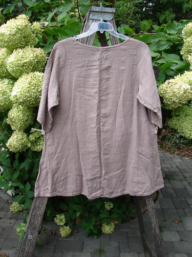 Barclay NWT Linen Lucida Top Moon Fern Oriel Size 0 on clear hanger, showcasing its flowy A-line shape and rounded neckline, set against lush greenery and pale hydrangeas.