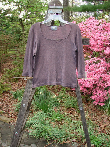 2000 Litmus Squareneck Top Unpainted Iron Size 1 displayed on a wooden rack, showcasing its unique neckline, neat stitching, and slight flare at the hips for an elegant drape.