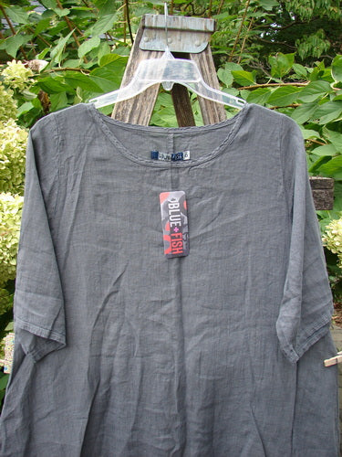 Barclay NWT Linen Lucida Top Unpainted Diatom Size 0, featuring a loose A-line shape, rounded neckline, and three-quarter sleeves, hangs on a wooden ladder with a Blue Fish tag attached.