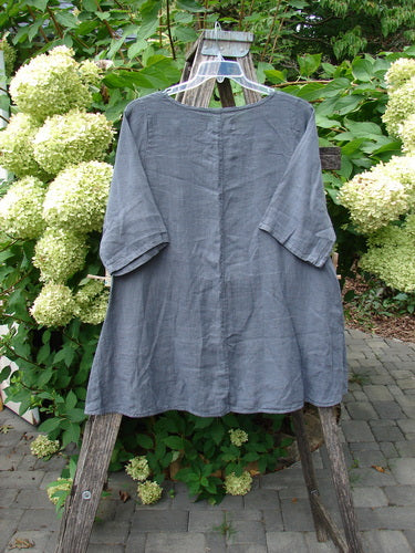 Barclay NWT Linen Lucida Top Unpainted Diatom Size 0, featuring elbow-length sleeves and a rounded neckline, elegantly draped on a weathered wooden ladder, showcasing its flowy A-line shape.