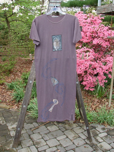 1996 Long Tee Dress Lolly Flower Violet Field Altered Size 0 displayed on a wooden rack, showcasing its short wide sleeves and elegant rounded paneled neckline, with signature Blue Fish patch.