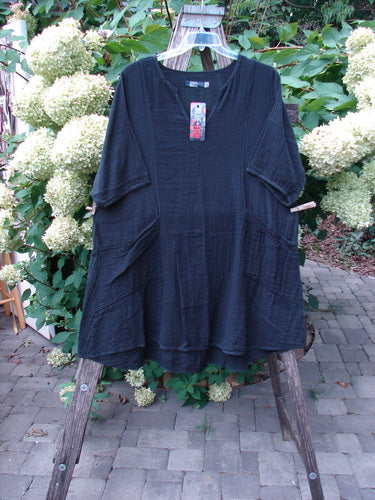 Barclay NWT Gauze Keyhole Bliss Pocket Dress Unpainted Black Size 0 hangs on a wooden display. It features a crinkled texture, front patch pockets, and a keyhole neckline, capturing Bluefishfinder.com's vintage style.
