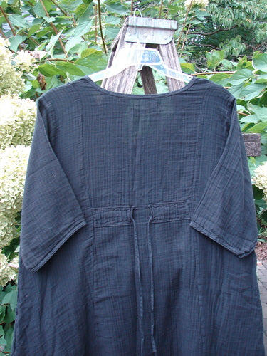 Barclay NWT Gauze Keyhole Bliss Pocket Dress Unpainted Black Size 0, featuring a keyhole neckline, three-quarter sleeves, and waist tie, displayed outdoors against lush foliage on a hanger.