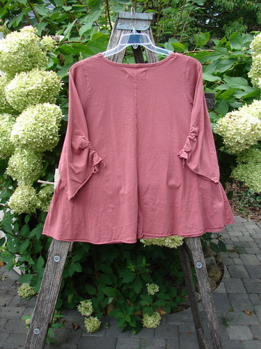 Barclay NWT Draw Gather Sleeve Cafe Top Free Bird Desert Size 0, featuring a swinging A-line shape and flared sleeves with ruffle detail, displayed against a garden backdrop on a wooden trellis.