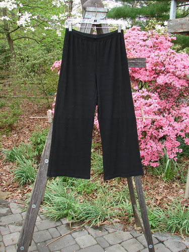 2000 Rayon Lycra Rib Flare Pant Unpainted Black Size 0 draped on a wooden ladder, showcasing its full elastic waistline and slightly flared bottom with superior drape and fall.