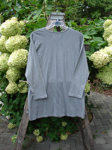 Barclay NWT Long Sleeved Studio Tee in Grey Moonlight, featuring a straighter shape and rounded neckline, displayed on a rustic ladder against a lush garden backdrop. Perfect for expressing individuality.