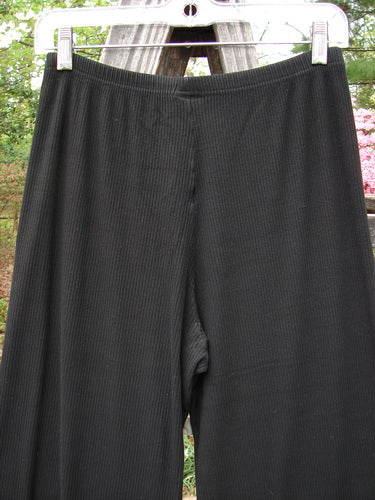 2000 Rayon Lycra Rib Flare Pant Unpainted Black Size 0, hanging on a clothesline, showcasing its full elastic waistline and slightly flared bottom against an outdoor backdrop.