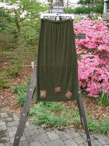 2000 Patched Rayon Lycra Rib Linear Skirt Green Oak Heather Size 0 displayed draped on a wooden ladder outdoors, highlighting its full elastic waistband and slightly flared lower shape.