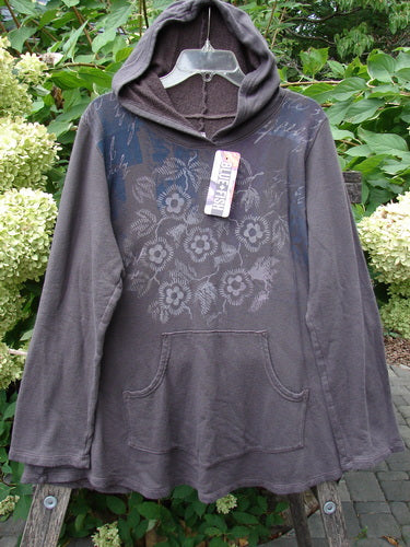 Barclay NWT Fleece Sweet Pocket Hoodie features a muted gray-brown color, cordless hood, kangaroo pocket, and subtle floral print across the chest, hanging outdoors, showcasing its cozy, organic fabric.