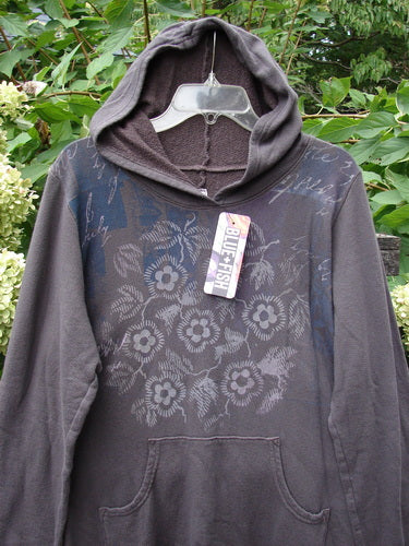 Barclay NWT Fleece Sweet Pocket Hoodie Contour Daisy Brown Sparrow Size 0 displayed outdoors on a hanger, featuring a cordless hood, kangaroo pocket, and an all-over floral and script pattern. Retail tag reads “BLUE FISH.”