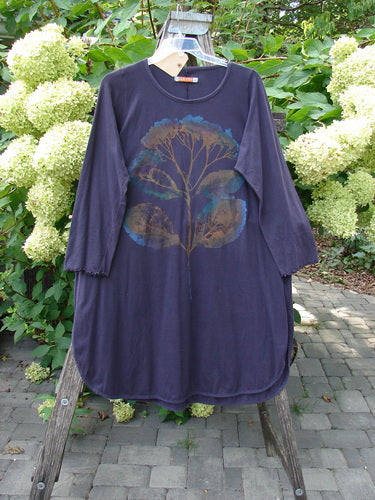 Barclay NWT Natalia Tunic Dried Floral Metallics Plum River Size 1, featuring long sleeves, a rounded neckline, and botanical motifs, displayed on a wooden hanger outdoors against hydrangea blooms.
