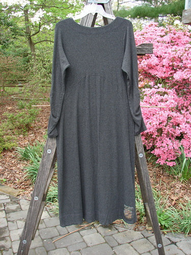 A long Julia Dress from the Holiday 2000 Collection in Charcoal Heather, displayed on a wooden ladder, showcasing its sectional front crisscross, gathered forearms, and soft rounded neckline.