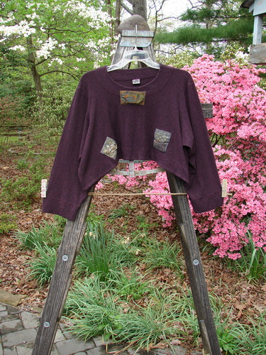 2000 Patched Rayon Lycra Rib Overtop in Cassis Heather Size 1, displayed on a wooden ladder outdoors, highlighting its textured ribbing and unique painted patches.