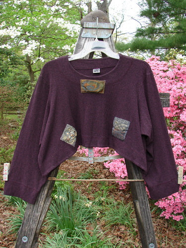 2000 Patched Rayon Lycra Rib Overtop Cassis Heather Size 1 displayed on a wooden rack, showcasing its textured, heavy yet flowing fabric and unique Celtic-themed painted patches.