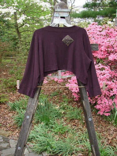 2000 Patched Rayon Lycra Rib Overtop Cassis Heather Size 1 displayed on a wooden stand, featuring a dramatic hemline and exterior stitchery with Celtic-themed patches.