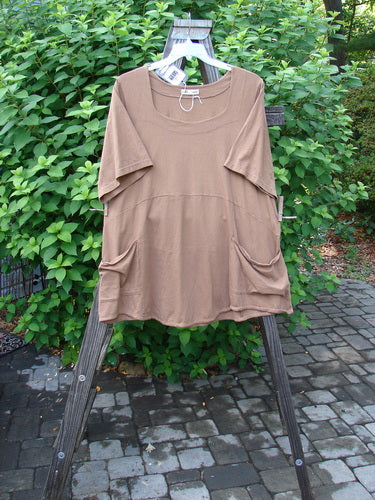 Image alt text: Barclay NWT Be There Top - Brown shirt with pockets on a wooden clothes rack, made from organic cotton. Empire waist seam, wide full pleats, forever skirt flair, beautifully squared double paneled deeper neckline. Bust 54, Waist 56, Hips 60, Hem Circumference 80, Length 32.