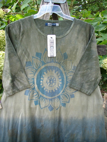 Barclay NWT Wander Tunic Tee Sunflower Mottled Vintage Camo Size 0, featuring a stylized sunflower design, hung outdoors. The piece exhibits a tunic-style with slight A-line flair and long sleeves.