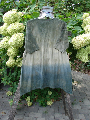 Barclay NWT Wander Tunic Tee Sunflower Mottled Vintage Camo Size 0, hand-dyed with ombré hues, displayed on a wooden easel, featuring three-quarter sleeves, a rounded neckline, and varying tunic length.