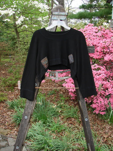 2000 Patched Rayon Lycra Rib Overtop Black Size 0 displayed on a wooden rack, highlighting its unique upward scooping hemline and Celtic-themed painted patches, perfect for layering and travel.