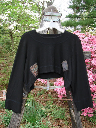 Black 2000 Patched Rayon Lycra Rib Overtop Size 0 displayed on a clothes hanger outdoors, showcasing its upward scooping hemline, exterior stitchery, and unique Celtic-themed painted patches.