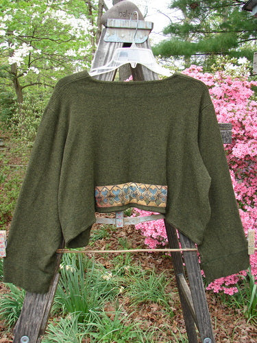 2000 Patched Rayon Lycra Rib Overtop Green Oak Heather Size 1 displayed outdoors on a wooden swing, highlighting its unique hemline and exterior stitchery.