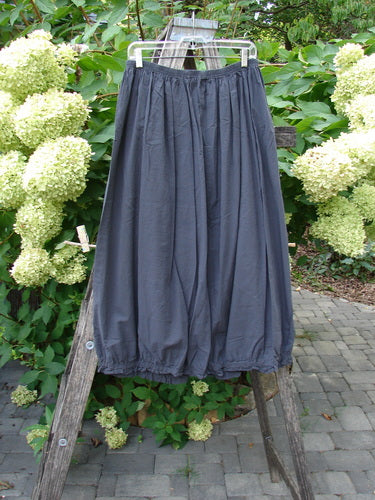 Barclay NWT Batiste Airy Lawn Skirt Unpainted Black Sand Size 0, displayed hanging on a ladder, features a full elastic waistline and gathered hem, highlighting its unique barrel shape.