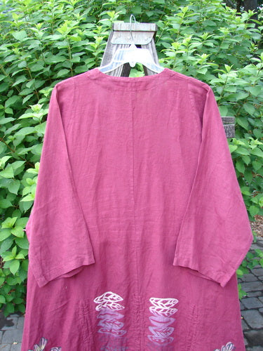 Barclay Linen Venetian High Vent Tunic Dress Cornflower Berry Size 2: A pink shirt with a white design on it, featuring a feminine hourglass shape, wider hip and hemline, and softly rolled neckline.