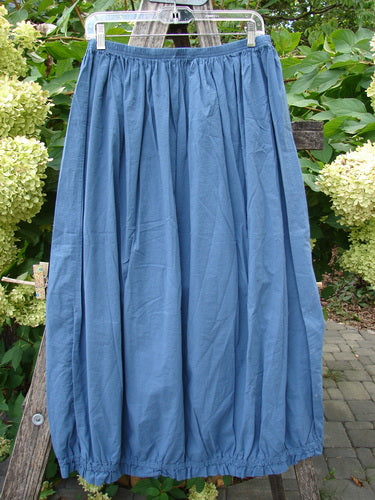 Barclay NWT Batiste Airy Lawn Skirt in Echo Blue, ankle-length, gathered, with a full elastic waist and hem, displayed outdoors on a hanger, embodying Blue Fish's unique vintage style.