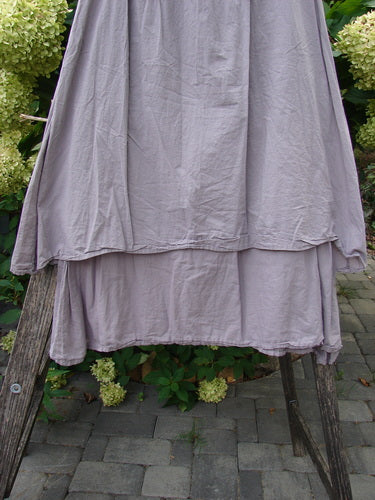 Barclay NWT Batiste Two Story Shaunting Skirt showcases a soft mauve, tiered design draped gracefully over wooden supports, highlighting its full elastic waistline and flowing double-layered cotton batiste.