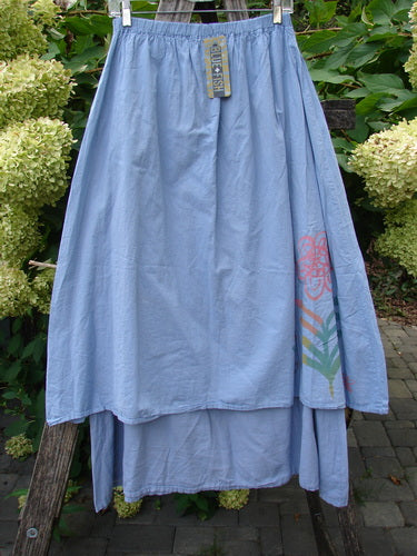 Barclay NWT Batiste Two Story Shaunting Skirt in Sky, featuring a lightweight, tiered cotton design with elastic waistband, floral and stripe patterns, hanging outdoors with brand tag visible.