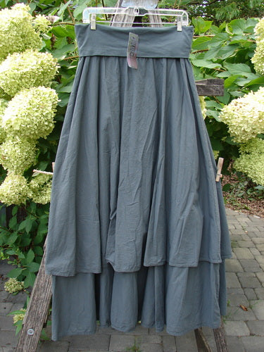 Barclay NWT Batiste Fold Over Stardust Tier Skirt in Atlas Grey Size 0, displayed outdoors on a hanger, showcasing its tiered A-line design and generous, flowing form against a patio backdrop.