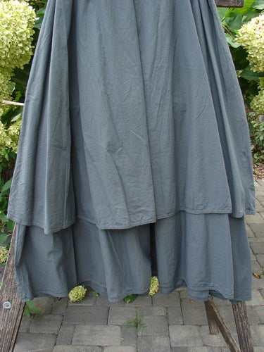 Barclay NWT Batiste Fold Over Stardust Tier Skirt Atlas Grey Size 0 displayed on a wooden hanger in a garden, showcasing its two-tiered, A-line flair with a forgiving waistline and generous hips.