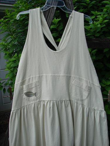 Image alt text: "New With Tag Tadpole Jumper, a white dress on a clothesline, featuring adjustable shoulder straps, a sweeping hemline, a criss-cross lower back, and round bottomed pockets."