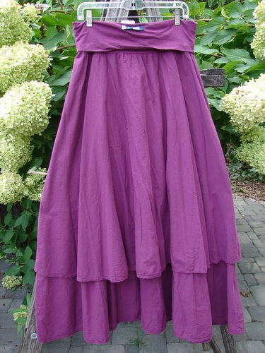 Barclay NWT Batiste Fold Over Stardust Tier Skirt Tyrian Berry Size 0, featuring a tiered, flowing design with a wide waistband, displayed outdoors against a background of hydrangeas and patio elements.