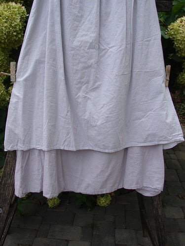 Barclay NWT Batiste Two Story Shaunting Skirt in Pearl Smoke, featuring a double-layered design with an elastic waist, hangs drying on a wooden support, embodying Bluefishfinder.com's vintage charm.