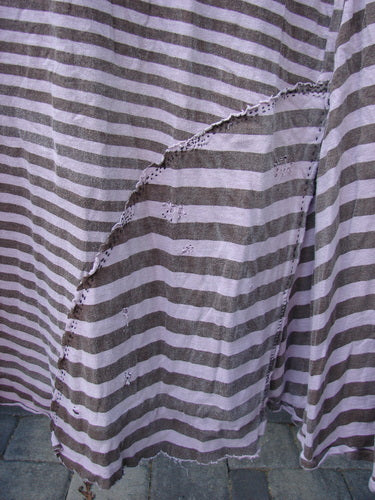 Magnolia Pearl Cotton Dylan Dress Hand Mended Lavender Stripe OSFA features alternating light and dark stripes, diagonal seam detail, and visible ruffle, showcasing its unique texture and craftsmanship.