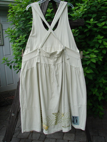 A white dress with adjustable shoulder straps, a sweeping hemline, and a criss-cross lower back. Features a double paneled waistline, round bottomed pockets, and a gold fish theme paint.