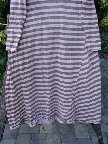 Magnolia Pearl Cotton Dylan Dress Hand Mended Lavender Stripe OSFA displayed on a wooden bench. Features include horizontal stripes, a rounded neckline, long sleeves, and handmade stitch details, embodying unique vintage style.