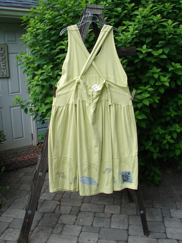 A yellow dress with fish on it, featuring a huge sweeping hemline, adjustable shoulder straps, and a criss-cross lower back. The dress has a downward yoked and slight empire double paneled waistline, two round bottomed pockets, and a bass and moon theme paint with a sky blue fish patch. Made from organic cotton, this New With Tag Tadpole Jumper is from the Summer Collection of 2000. Bust: 40 and Open, Waist: 50, Hips: 60, Length: 46 to 52 inches.