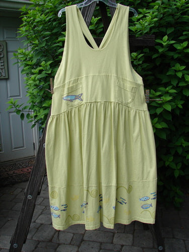 A New With Tag Tadpole Jumper dress with a fish pattern on a yellow background. Features include adjustable shoulder straps, a sweeping hemline, a criss-cross lower back, and round bottomed pockets. Perfect for a unique, individualized look.