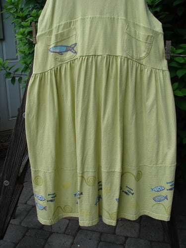 Image alt text: "1999 NWT Tadpole Jumper with fish and fish pattern, citron color, adjustable shoulder straps, huge sweeping hemline, criss-cross lower back, double paneled waistline, round bottomed pockets, school theme paint, Blue Fish patch"