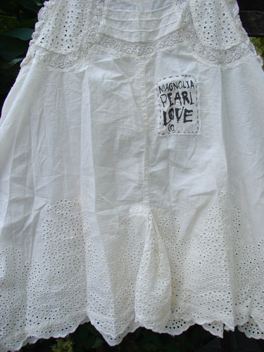 Magnolia Pearl NWT Embroidered Eyelet Cotton Clementine Tank True OSFA features intricate eyelet lace detailing along the hem, laced straps, pintucked front and back, and the brand's signature patch, embodying timeless, creative individuality.