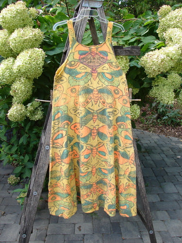 Magnolia Pearl NWT Cotton Fleece Lepidoptera Lana Tank Dress Butterfly Sunnies OSFA displayed on a wooden ladder, showcasing its vibrant butterfly print and raw-edged, apron-style design.