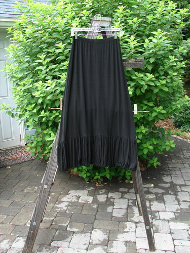 2000 Rayon Lycra Bubble Skirt Unpainted Black Size 1: A black skirt with a super gathered bubble bottom and tapered elastic hemline, hanging on a wooden ladder.