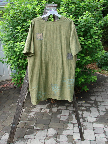 2000 Cross Dye Linen Patched Downtown Jacket, size 2. A green shirt with exploration theme patches on a wooden stand.