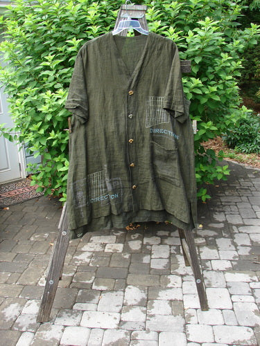 2000 Cross Dye Linen Downtown Jacket Directional Oregano Size 2: A green shirt on a swinger with a wood post in the background.